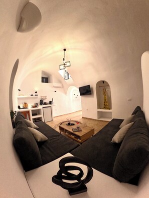 Ein gemütliches Wohnzimmer mit einer Couch, einem Couchtisch und einer modernen Küche im Hintergrund.