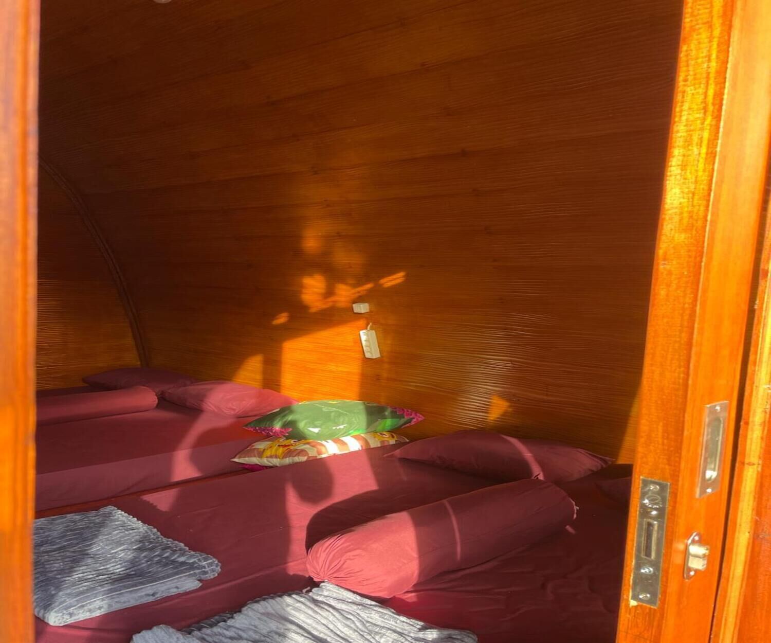Ein gemütlicher, holzgetäfelter Innenraum mit einem Bett, Kissen und einem kleinen Tisch.