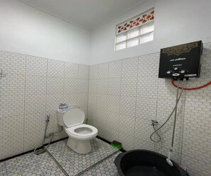 Ein Badezimmer mit Toilette, Dusche und einer schwarzen Badewanne.