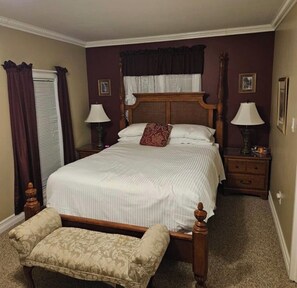 A bedroom with a four-poster bed, two bedside tables with lamps, a wooden bench, and a window with curtains. - Private Room, Walk to Niagara Falls & Clifton Hill + Free Parking (Niagara Falls)