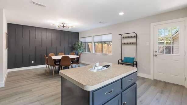 A modern kitchen with a dining area, a built-in island, and a view of the outside. - Chic Contemporary Home w/ Park + Garage/Pets ok (Conroe)