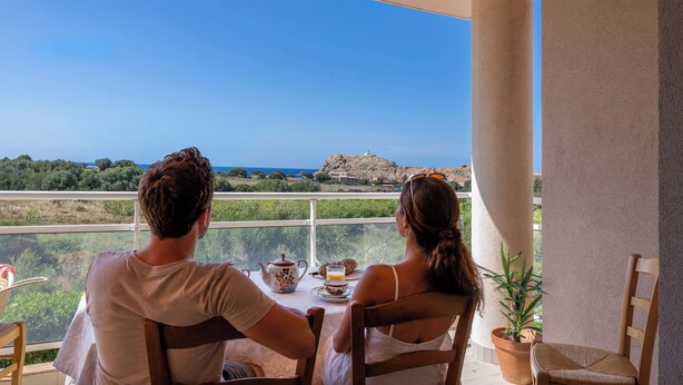 A couple dining at a table with a view of the sea and a hill. - Casa Luiggina – Appartement de charme avec vue mer au cœur de L’Île-Rousse (L'Île-Rousse)