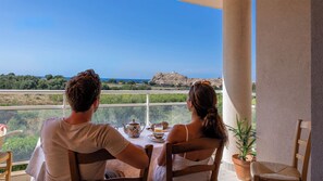 A couple dining at a table with a view of the sea and a hill. - Casa Luiggina – Appartement de charme avec vue mer au cœur de L’Île-Rousse (L'Île-Rousse)