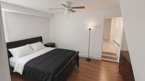 Camera da letto con un letto, un comodino, una lampada da terra, una ventola a soffitto e una scala che conduce a un piano superiore.