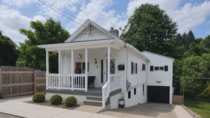 Una casa a un piano con veranda, garage e giardino recintato.
