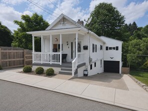 Ein eingeschossiges Haus mit Veranda, Garage und umzäunter Garten.