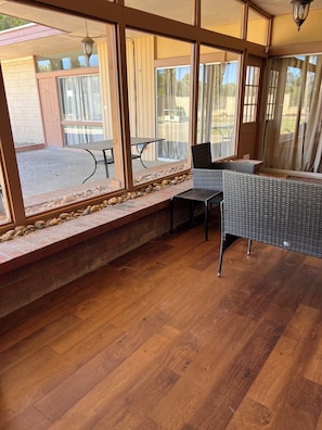 Una habitación con piso de madera, un banco y una mesa.