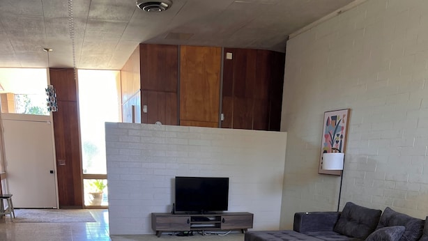 A modern living room with a flat-screen TV, a sectional sofa, a coffee table, and a patterned rug.