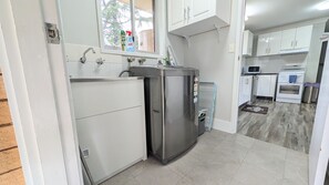 A compact kitchen with white cabinets, a stainless steel refrigerator, a microwave, and an oven.