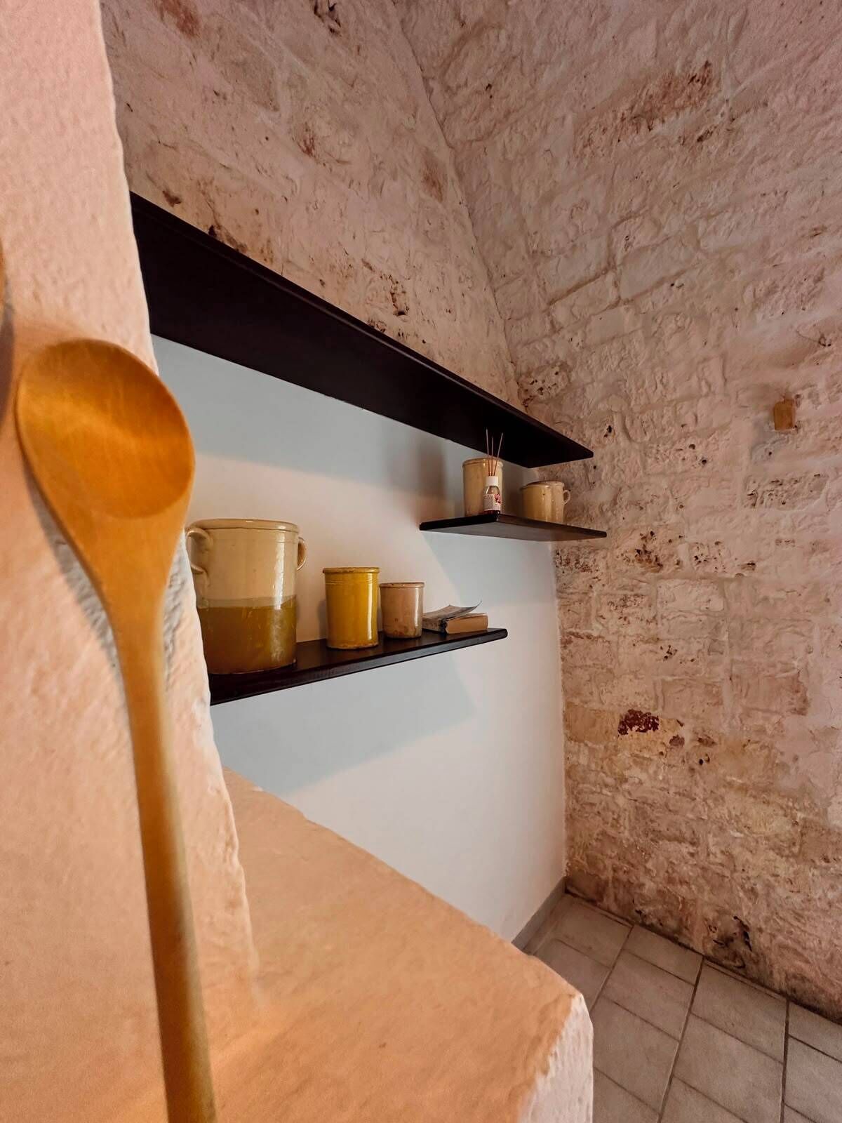 Une cuisine rustique avec des murs en briques apparentes, des étagères en bois et une cuillère en bois.