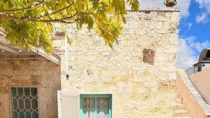 A stone building with a turquoise door, a window with a grid pattern, and a staircase. - Giardino dei Trulli Cummerse (Castellana Grotte)