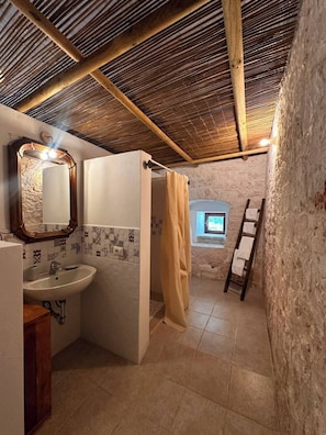 A rustic bathroom with a wooden ceiling, a sink, a mirror, and a shower curtain.