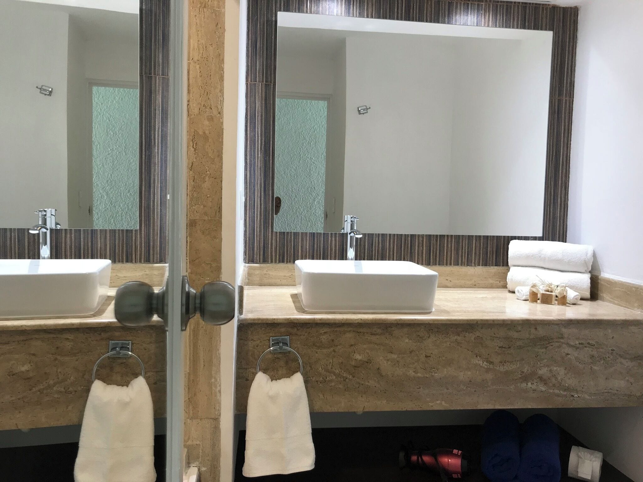 Un baño con dos lavamanos, un espejo grande y toallas.