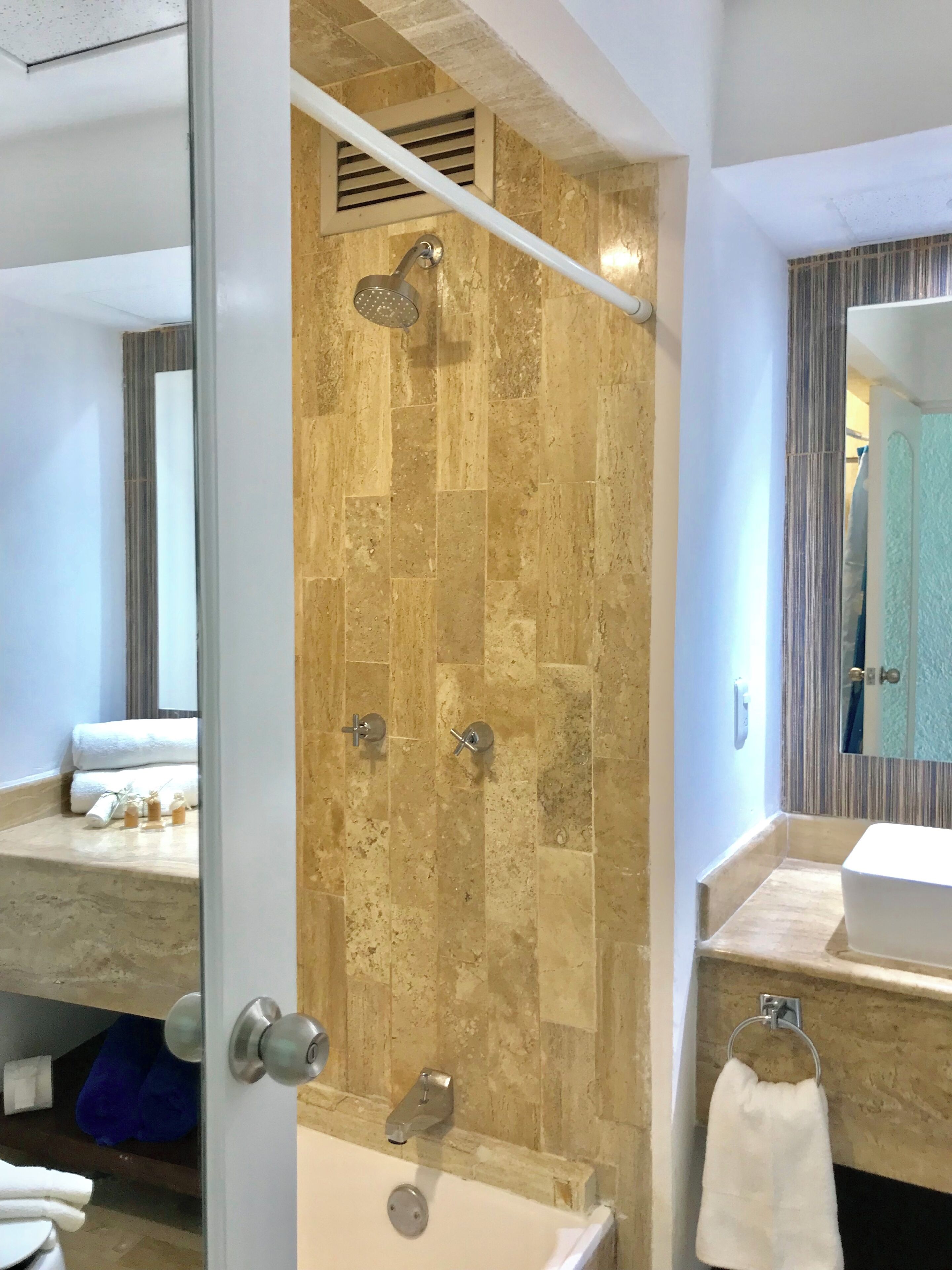 Un baño con ducha, lavamanos y espejo.