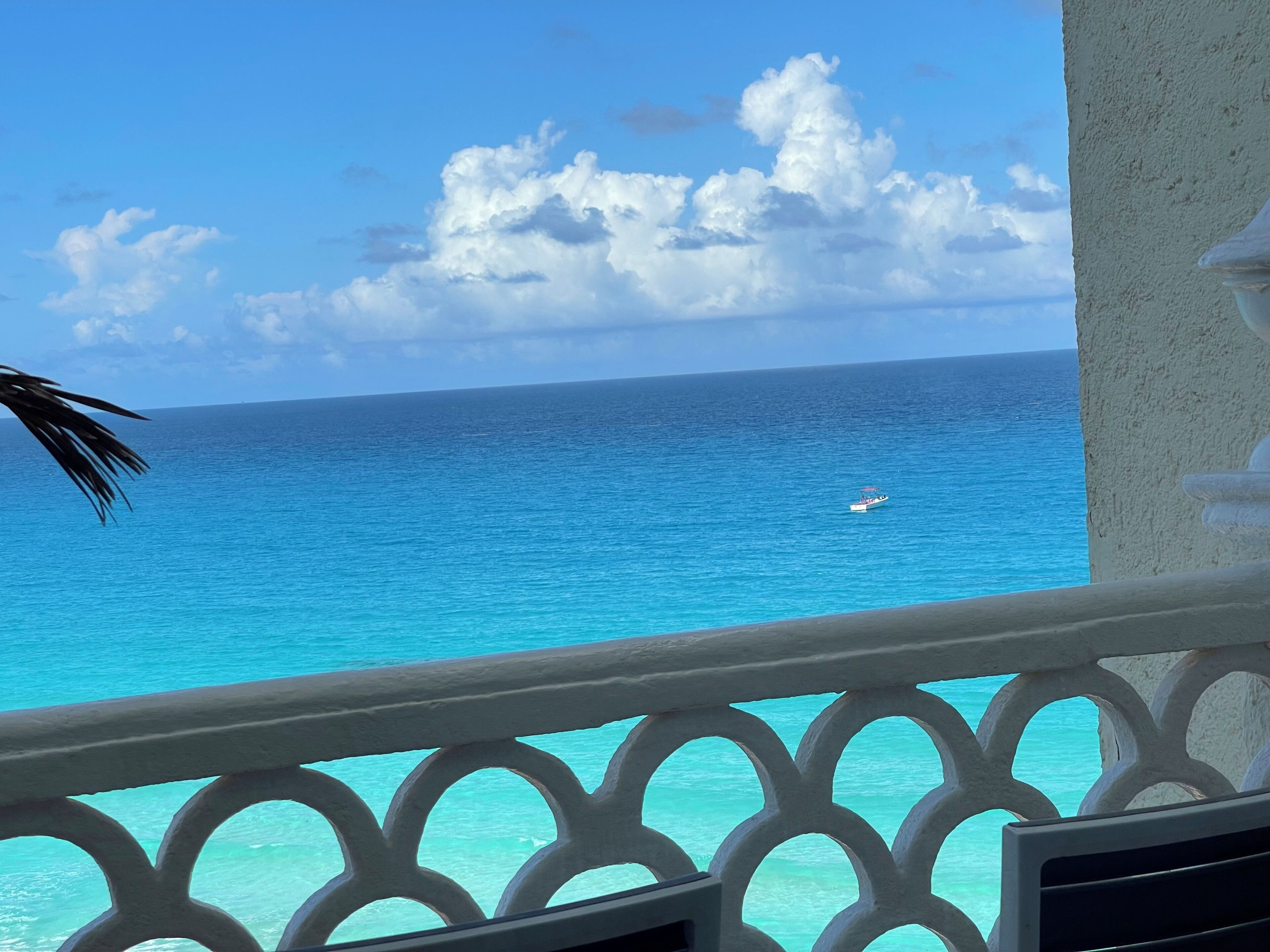 A balcony with a view of the ocean and a boat.