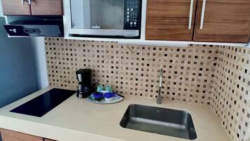 Una cocina con armarios de madera, microondas, fregadero y cafetera.