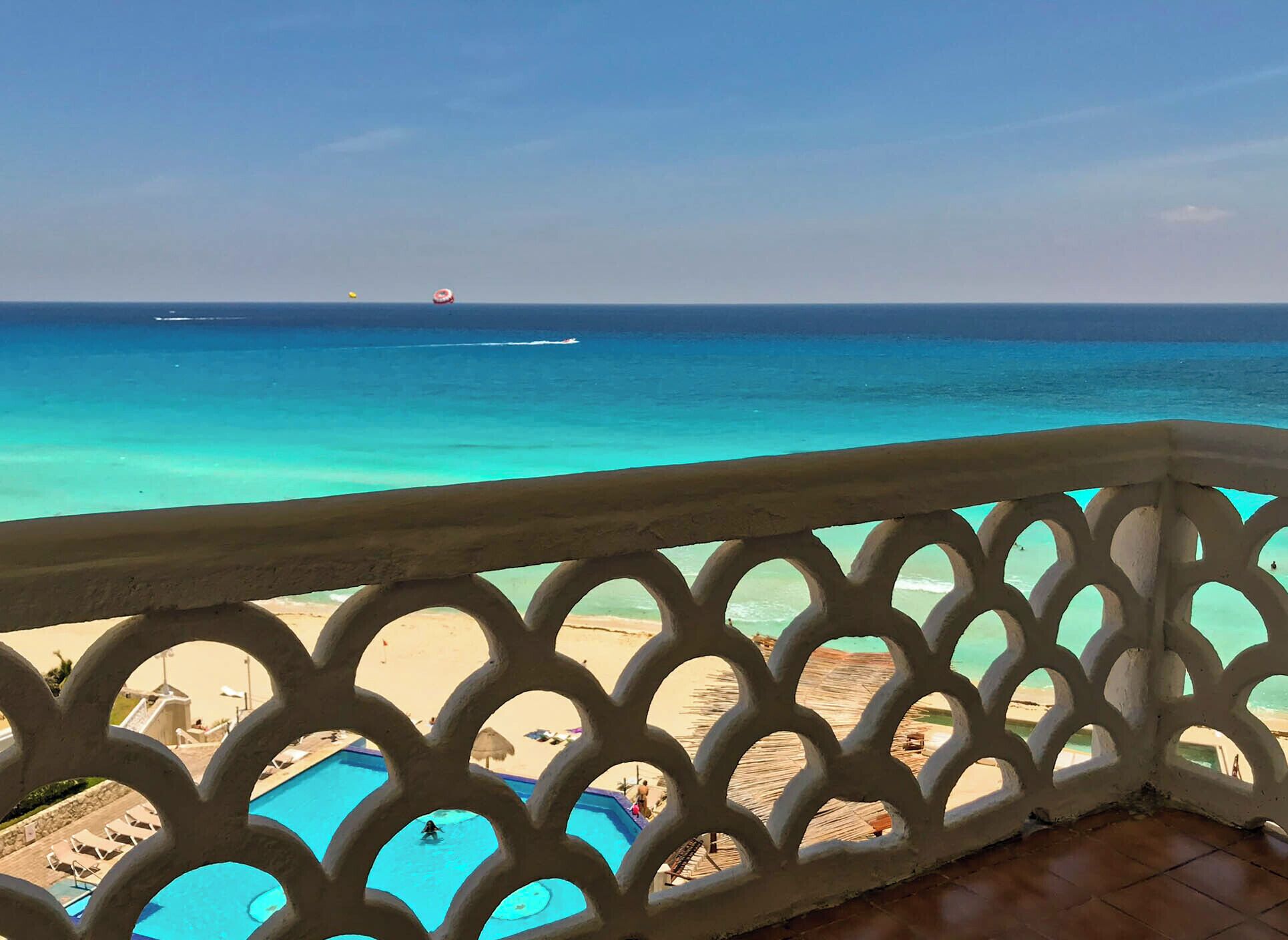 Uma varanda com vista para uma praia e uma piscina.
