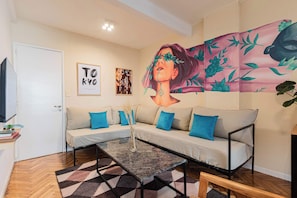 A living room with a sofa, a coffee table, and a wall mural. - MOT Rentals + Junin - 2 Bd (Buenos Aires)