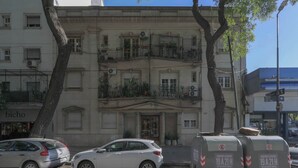 Un bâtiment à la façade classique, doté d’une double porte d’entrée et d’un balcon agrémenté de plantes en pot.