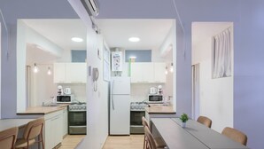 Une cuisine de taille réduite avec des meubles blancs, une table à manger et des chaises.