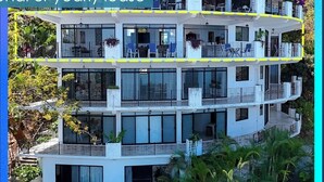 Un edifici de diverses plantes amb balcons, grans finestres i plantes a l'exterior.