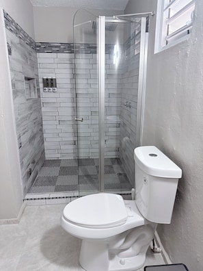 A bathroom with a glass-enclosed shower, a white toilet, and a tiled shower floor. - GOLDEN SECRETS 3 (YOUR MODERN CORNER) (San Antonio)