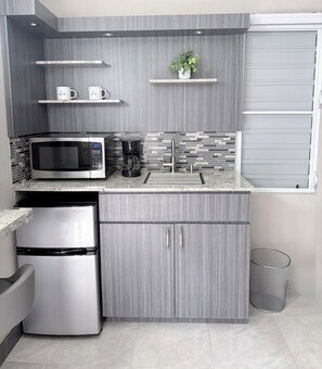 Una cocina moderna con un refrigerador de acero inoxidable, un microondas y una cafetera.