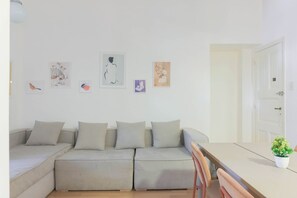 Un espacio habitable moderno con un sofá, una mesa de comedor y obras de arte en la pared.
