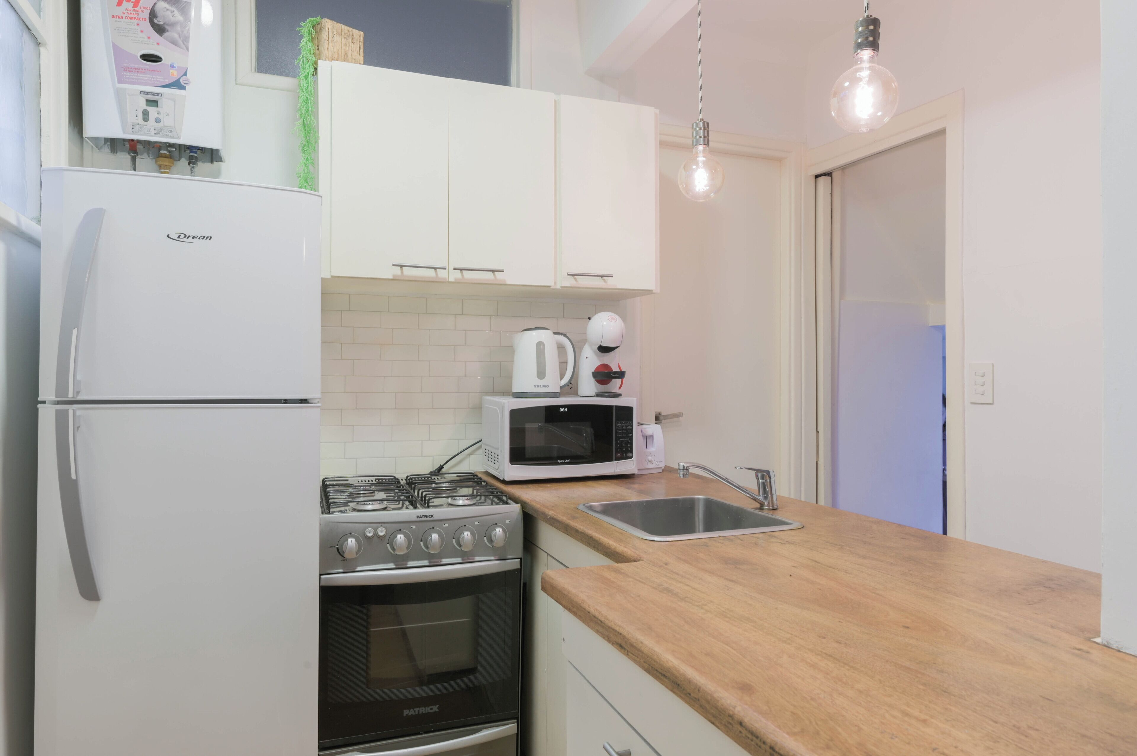 Une cuisine de taille réduite équipée d’un réfrigérateur, d’une cuisinière, d’un four à micro-ondes et d’un évier.