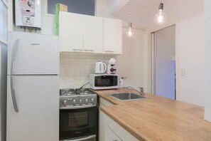 A compact kitchen with a refrigerator, stove, microwave, and sink.