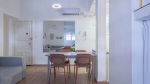 Moderni keittiö, jossa on ruokapöytä, tuolit ja sisäänrakennettu uuni.