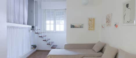 Uma sala de estar moderna com um sofá, uma escada e obras de arte nas paredes.