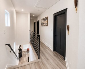 Um interior moderno com escada, portas pretas e um quadro na parede.