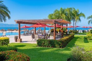 A poolside area with umbrellas, chairs, and a wooden pergola overlooking the ocean. - Gran Venetian Resort Stay Oceanfront by Monyxbnb (Puerto Vallarta)