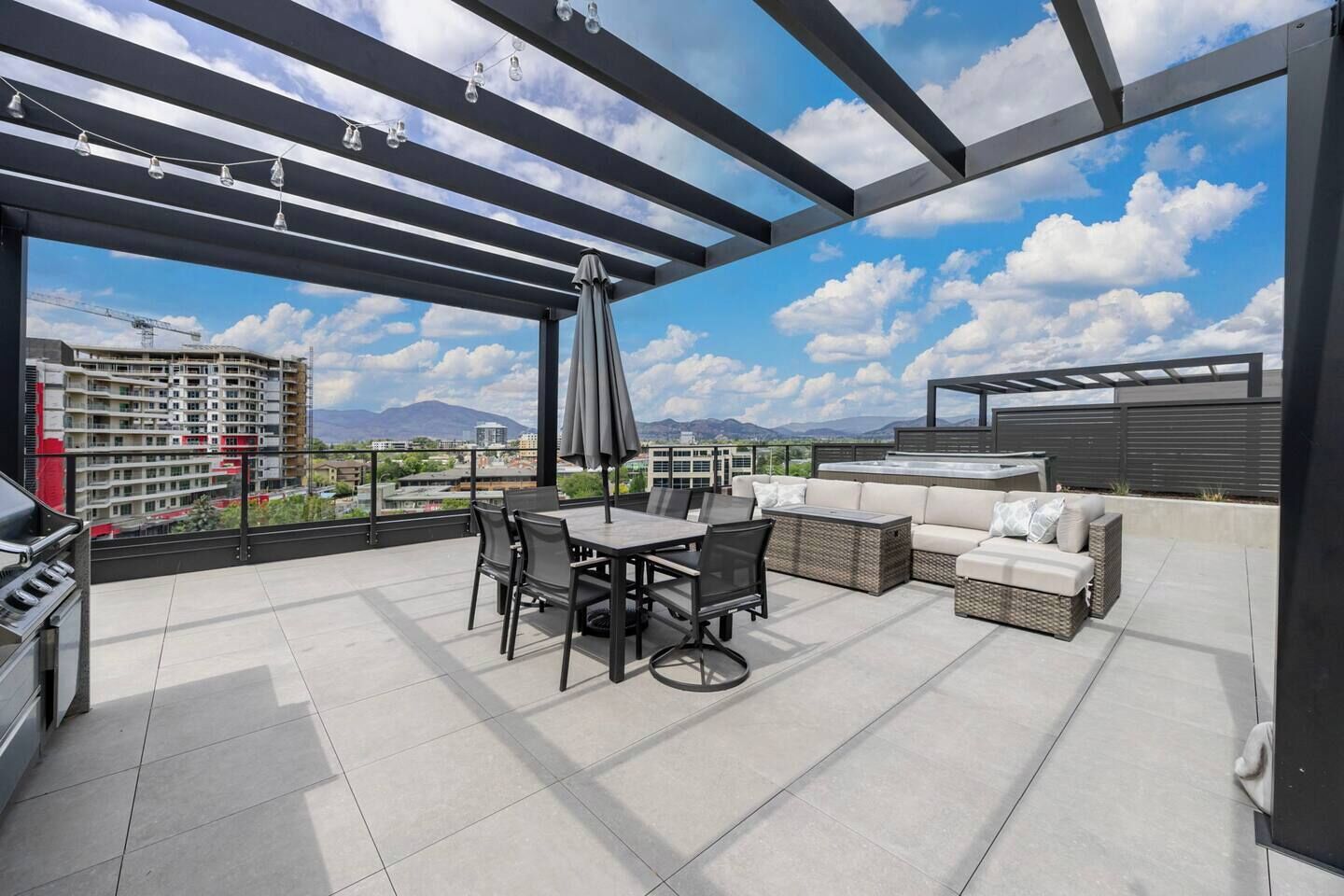 Une terrasse sur le toit équipée d’une table à manger, de chaises, d’un canapé et d’un barbecue.