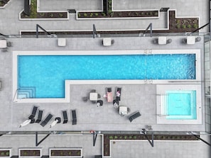 A rooftop swimming pool with multiple lounge areas and a smaller adjacent pool.