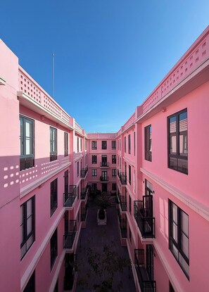 Ein pinkfarbenes Gebäude mit mehreren Balkonen und einem zentralen Innenhof.