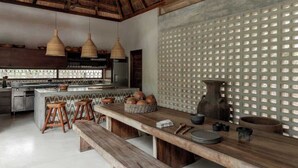 Une cuisine dotée d’un îlot central, de tabourets en bois, de luminaires suspendus et d’un mur à texture.