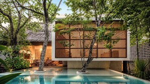 A pool area with a modern building, wooden fences, and lounge chairs. - Jungle Villa - Retreats - Pool - Yoga (Tulum)