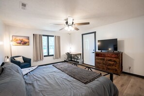 A bedroom with a bed, a desk, a chair, a television, and a ceiling fan. - Whiskey Trails Hollow (Manchester)