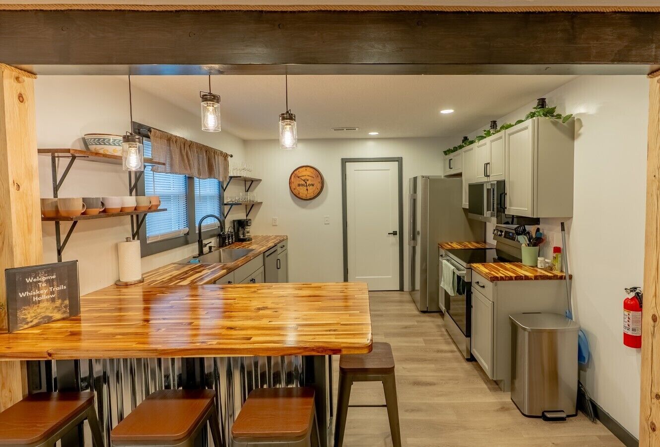 Una cucina con un'isola in legno, elettrodomestici in acciaio inossidabile e un estintore appeso al muro.