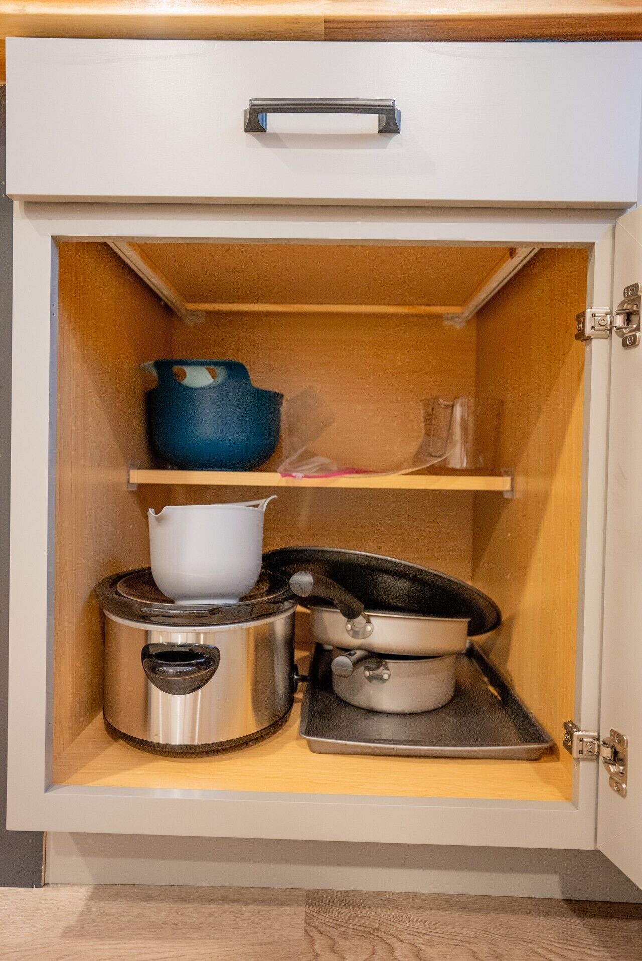 Eine Küchenschrank mit Herd, Töpfen und einem blauen Behälter.