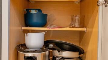 Eine Küchenschrank mit Herd, Töpfen und einem blauen Behälter.