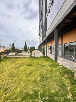 Een modern gebouw met een plat dak, grote ramen en een gazon binnenplaats.