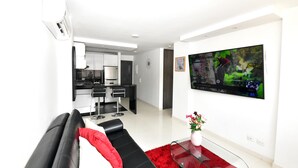 A modern living room with a black sofa, a red rug, and a flat-screen TV on the wall. - Stylish 12th Floor Apartment in the Heart of El Peñón (Cali)
