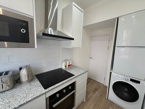 A kitchen with a stove, microwave, cabinets, and a washing machine.