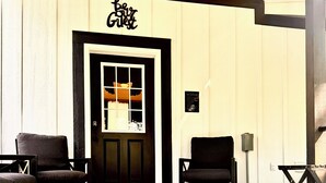 A room with a black door, two chairs, a bed, and a wall-mounted sign reading 'be my guest.' - Bungalow with Hot Tub in Birch Tree (Birch Tree)