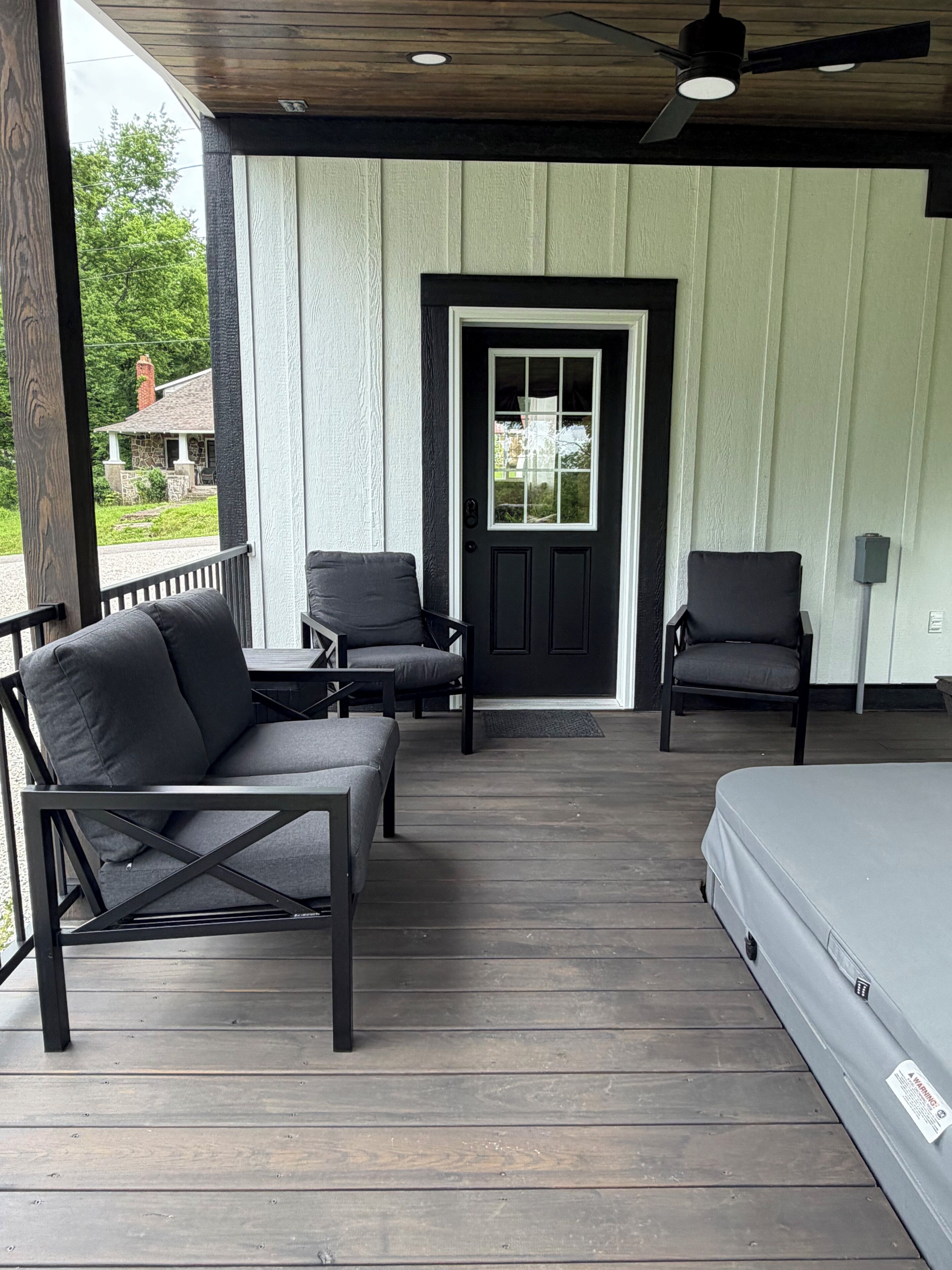 A porch with two chairs, a bench, and a bed.
