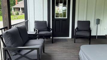 A porch with two chairs, a bench, and a bed.