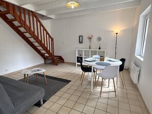 A living room with a staircase, a dining area with a table and chairs, a sofa, and a floor lamp. - NEW LISTING, Domaine de KER-PAULT, between St Cast and Matignon, apartment 5 minutes from the... (MATIGNON)